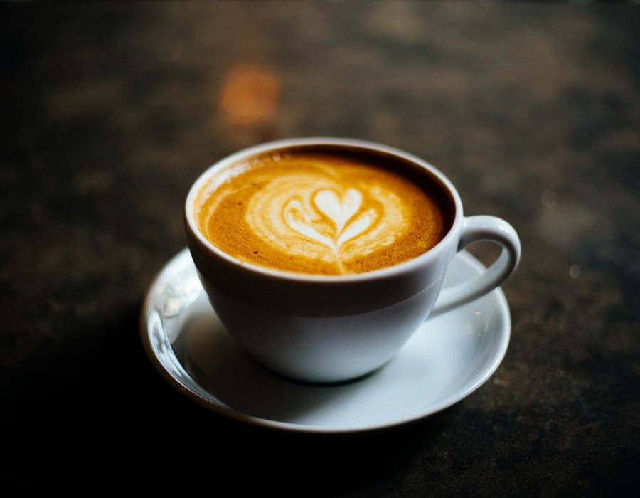 Flat white with heart latte art on a dark saucer
